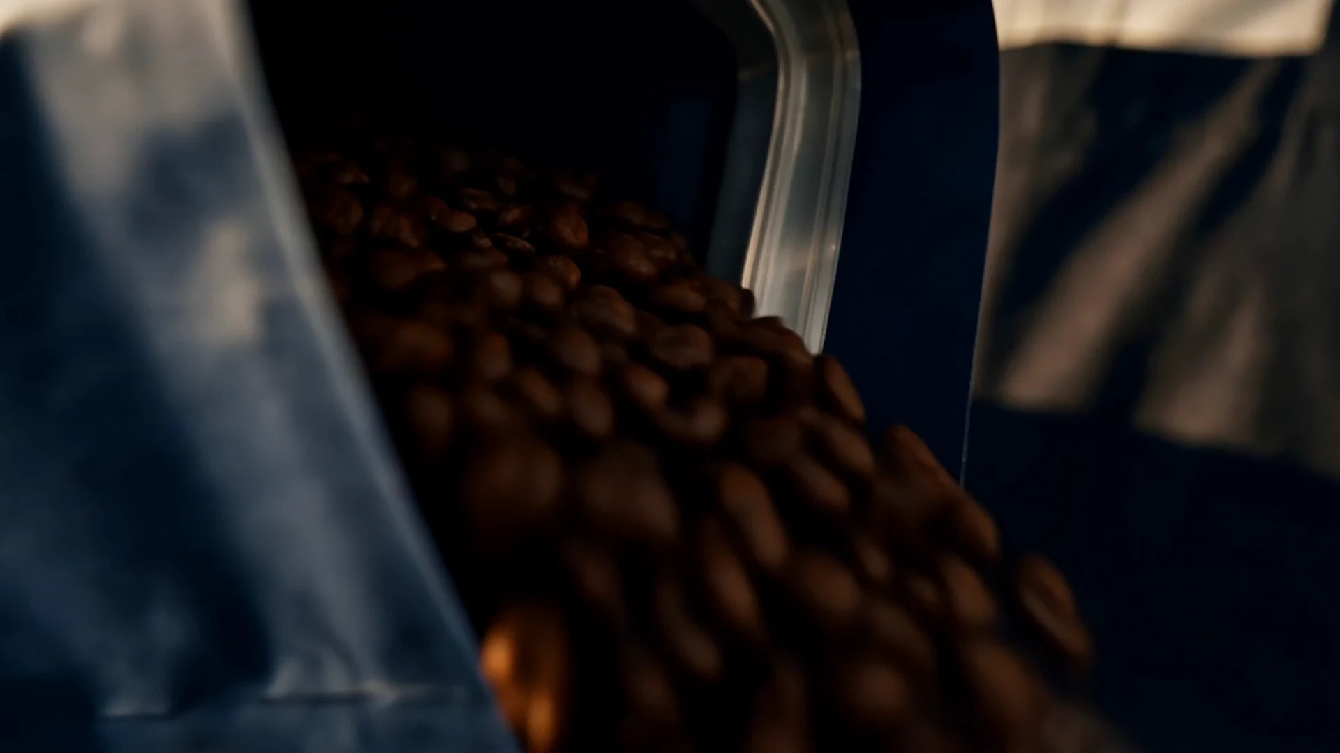Coffee beans moving through a grinder.